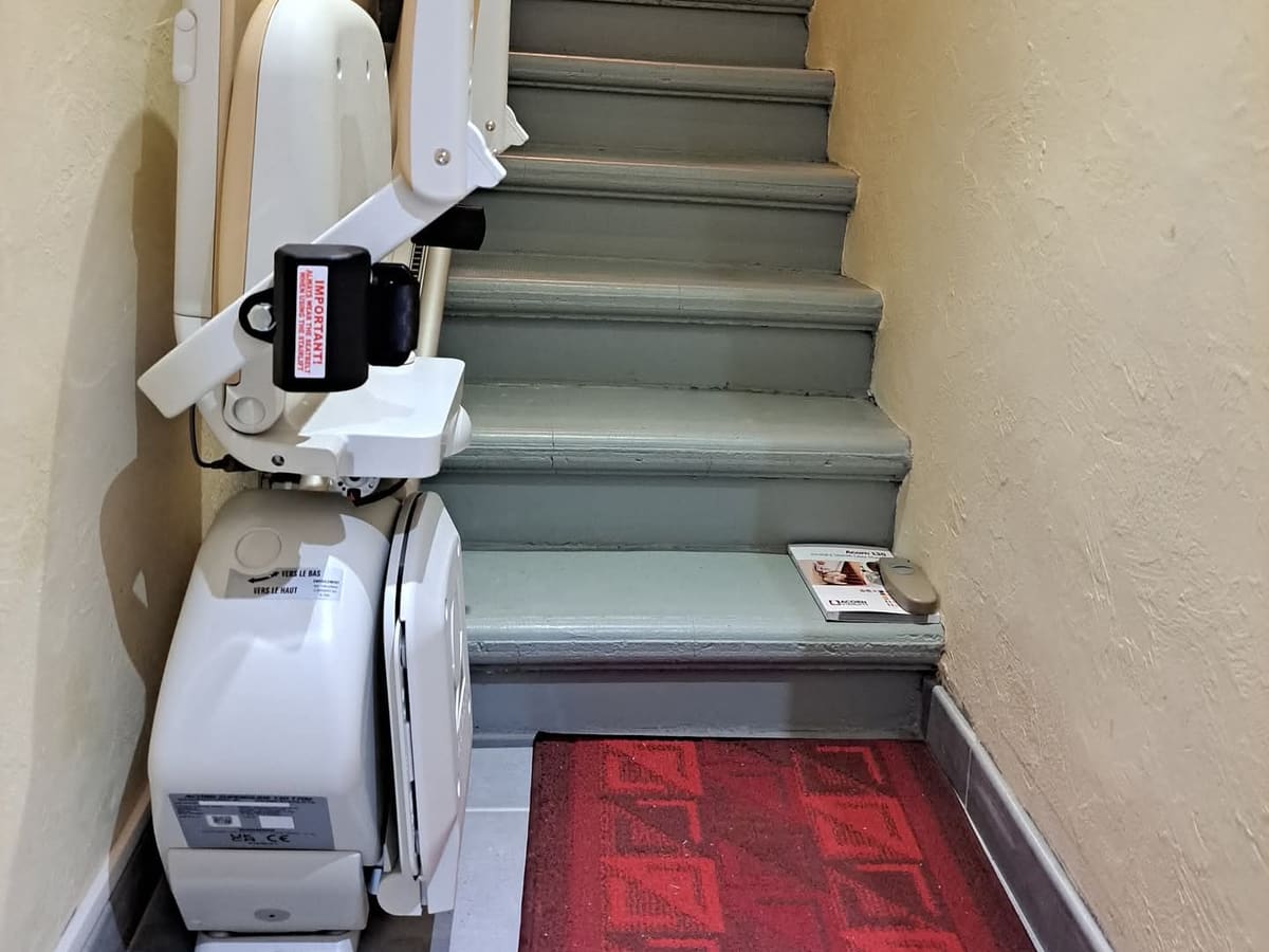 Exemple de monte-escalier droit dans un escalier intérieur étroit, siège replié au pied des marches